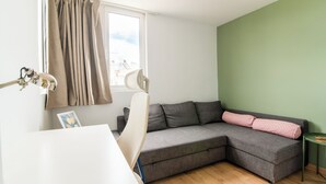 Una sala moderna con un sofá seccional gris, un escritorio blanco y una pared de acento verde.