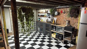 Una cocina con piso a cuadros, pared de ladrillo y plantas colgantes.