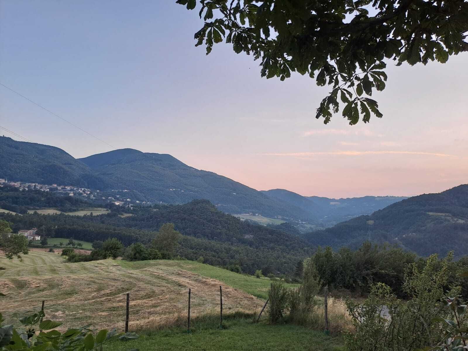 A rural landscape with rolling hills, a fenced field, and a distant village.