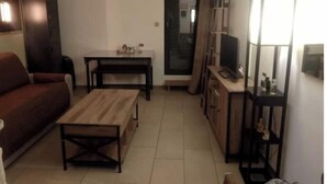 Ein Wohnzimmer mit einer Couch, einem Couchtisch, einer TV-Konsole und einem kleinen Tisch mit Gegenständen darauf.