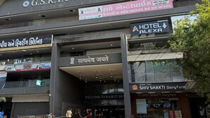 Terminal de autobuses G.S.R.T.C. Rajkot con un cartel que indica Hotel Alexa y la granja lechera Shiv Shakti.