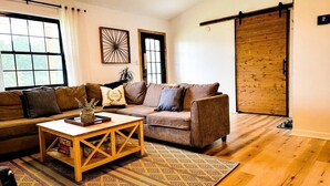 Una sala de estar acogedora con un sofá marrón, una mesa de centro de madera y un tapete estampado.
