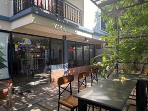 An outdoor seating area with a glass wall, wooden chairs, and a table.
