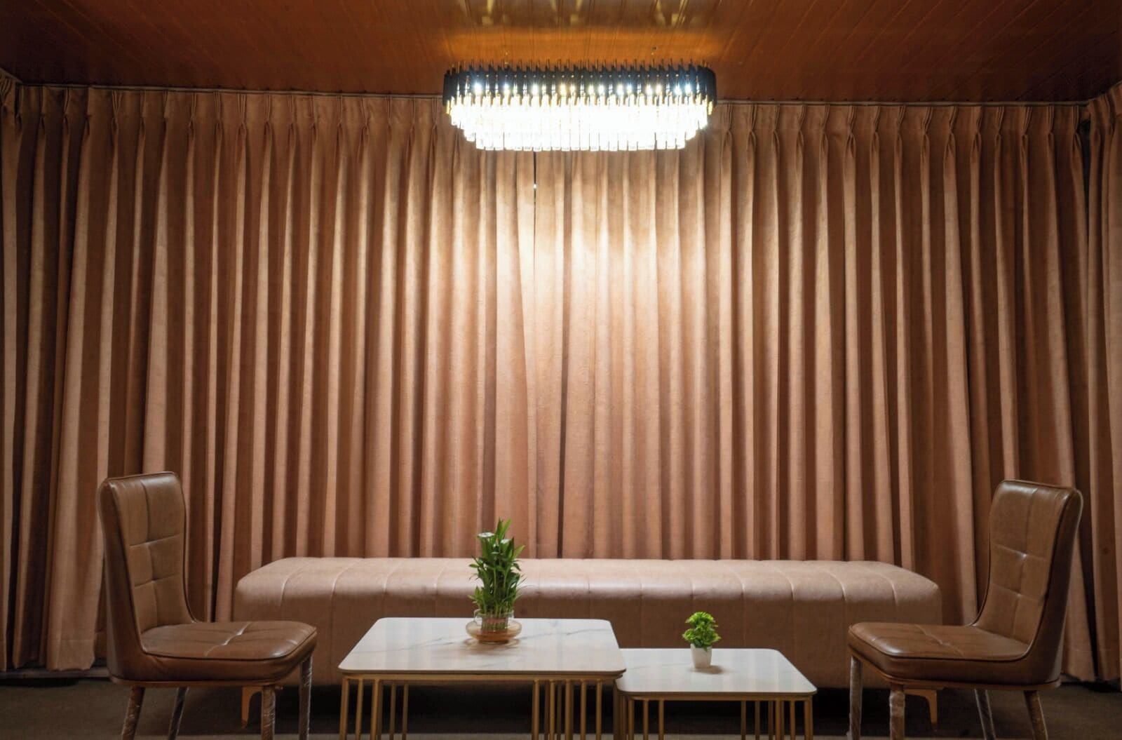 A room with a large, plush sofa, two wooden tables, and two leather chairs.