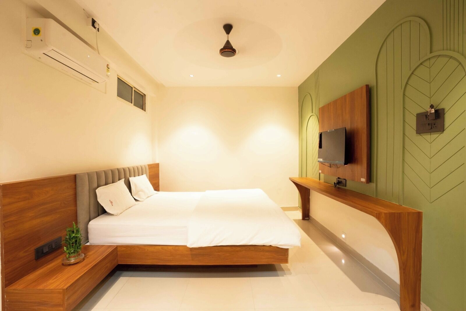 Una camera da letto moderna con un letto di legno, un comodino, una TV a parete e una ventola a soffitto.