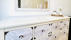 A white dresser with a mirror above it, a candle holder, and a vase with flowers. - Comfortable 1BR Lounge Westbahnhof (Vienna)