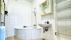 A bathroom with a bathtub, a sink, and a toilet. - Comfortable 1BR Lounge Westbahnhof (Vienna)