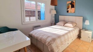 A bedroom with a bed, bedside tables, a window, and a view of the outside. - Charming Arès Villa: Beach, BBQ, & Fireplace! (Arès)
