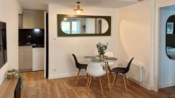 Un comedor con una mesa redonda, sillas y un espejo en la pared.