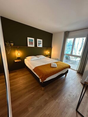 Ein Hotelzimmer mit einem Bett, zwei Nachttischlampen, einem fenster mit Vorhängen und Blick ins Freie.