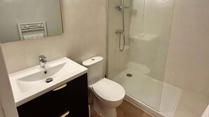 Une salle de bain moderne avec une douche à parois de verre, un lavabo blanc et des toilettes.