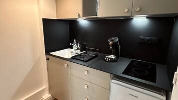 Una cocina compacta con estufa integrada, un lavamanos y un refrigerador pequeño.