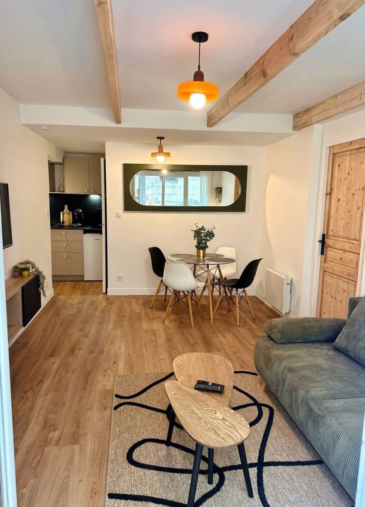 Un espacio habitable compacto con zona de comedor, un sofá y una mesita con un mando a distancia.