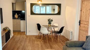 Un espacio habitable compacto con zona de comedor, un sofá y una mesita con un mando a distancia.