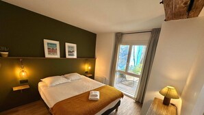 Une chambre à coucher avec un lit, des lampes de chevet, une fenêtre avec des rideaux et une petite table avec une lampe.