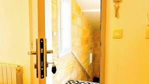Habitación de hotel con pared de piedra, una ventana, un radiador y una puerta con pomo.