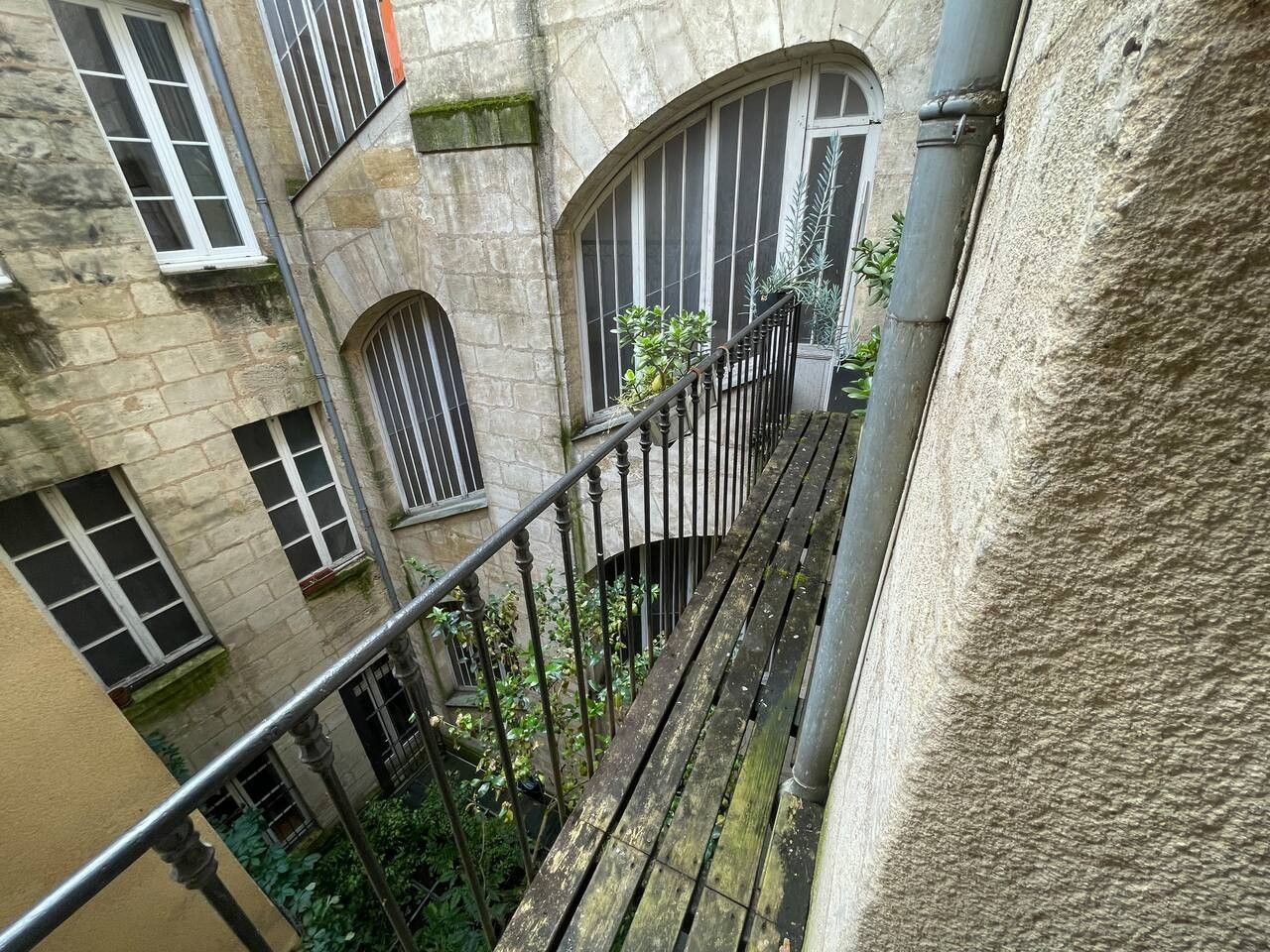 Ein Gebäude aus Stein mit mehreren Fenstern und einem Balkon mit Metallgeländer.