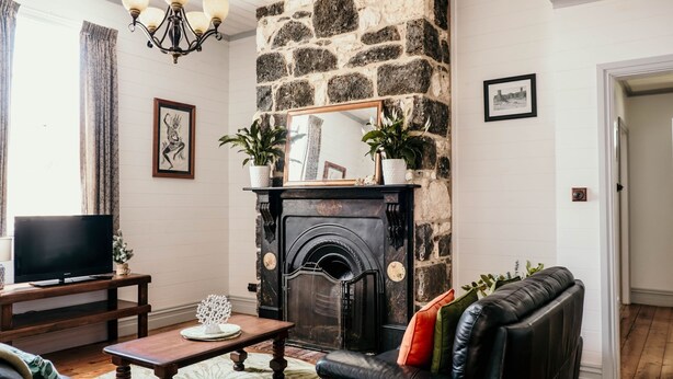 Ein Wohnzimmer mit Kamin aus Stein, einem Fernseher und einer Couch.