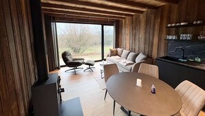 A modern interior with a wooden ceiling, a sofa, a dining table, and a kitchen area. - Holiday Home in Malmedy With Private Terrace (Malmedy)