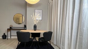 Ein zeitgemäßer Essbereich mit einem runden Tisch, zwei Stühlen, einer Vase mit Trockenblumen, einem Globus auf einem Beistelltisch und einem gerahmten Bild an der Wand.