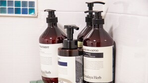 Trois flacons de produits pour les soins capillaires sont posés sur une étagère.