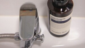 Un lavabo de salle de bain avec un robinet chromé et une bouteille de shampoing.