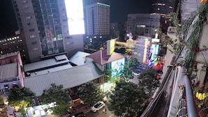 A nighttime cityscape with illuminated buildings, a prominent billboard, and a street with parked cars. - Prime Location 1BR – Nguyen Hue & Bitexco View (Thành phố Hồ Chí Minh)