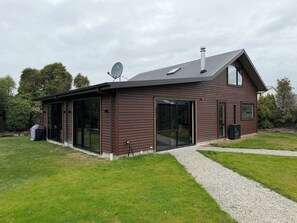 A modern house with a sloped roof, large sliding glass doors, and a satellite dish.