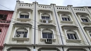 A multi-story building with a classical architectural style, featuring symmetrical windows and decorative moldings. - Shree krishna hotel  (Udaipur)