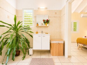 A bathroom with a white sink, mirror, and a potted plant. - Kaz A Doudou La – 2-bedroom apartment with terrace and garden, tropical calm (Saint-François)
