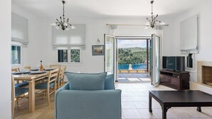 Uma sala de estar moderna com sofá, mesa de jantar, cadeiras, televisão e lareira.