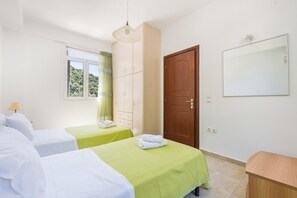A hotel room with two beds, a wardrobe, a mirror, and a window with a view of trees. - Luxury seafront plot villa, seaviews, p-pool, walk to beach- Villa Alex Meganisi (Meganisi)