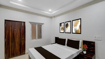 A bedroom with a bed, a wooden door, a window, and wall-mounted artwork.