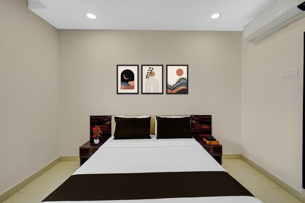 A hotel room with a bed, two nightstands, and three framed artworks on the wall.