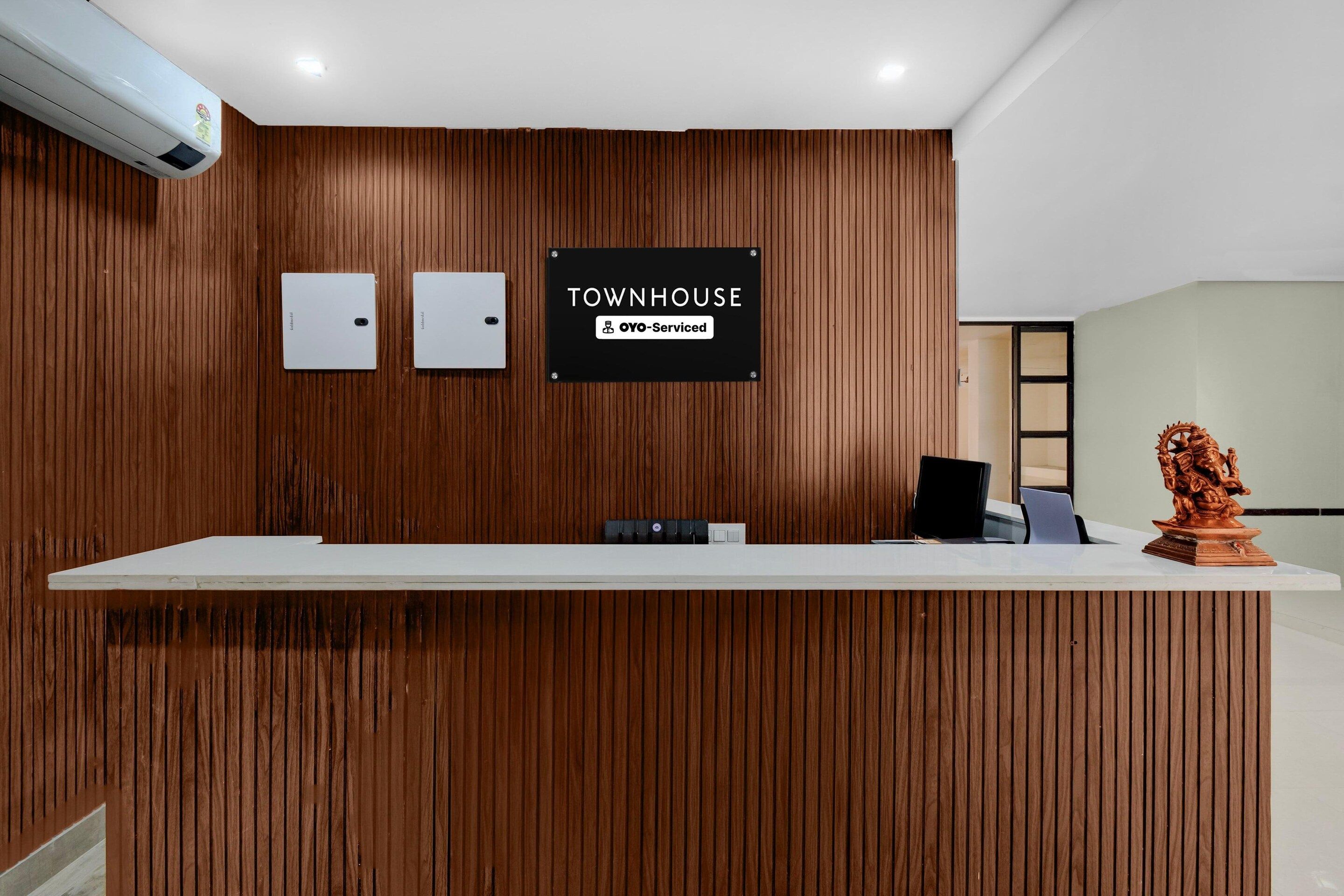 Een receptiebalie met een bord waarop 'TOWNHOUSE' en 'OYO-Serviced' staat.