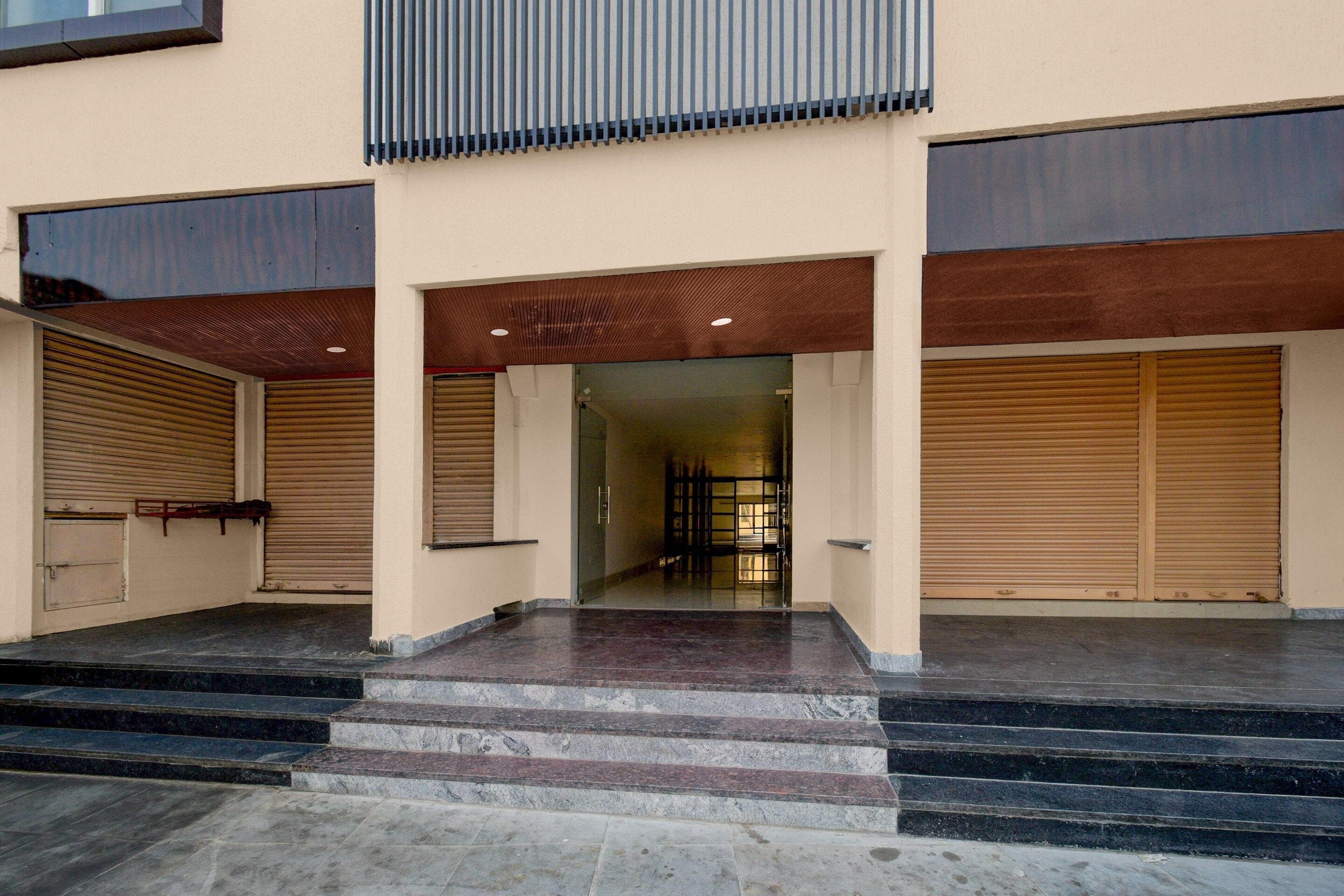 Fachada de un edificio con un conjunto de escalones que conducen a una puerta, flanqueada por dos puertas de garaje cerradas.