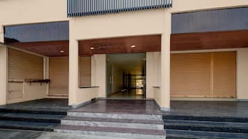 Fachada de un edificio con un conjunto de escalones que conducen a una puerta, flanqueada por dos puertas de garaje cerradas.