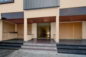 A building entrance with a set of steps leading up to a door, flanked by two closed garage doors. - Classic Hotel Lakshmi's Pride (Kurnool)