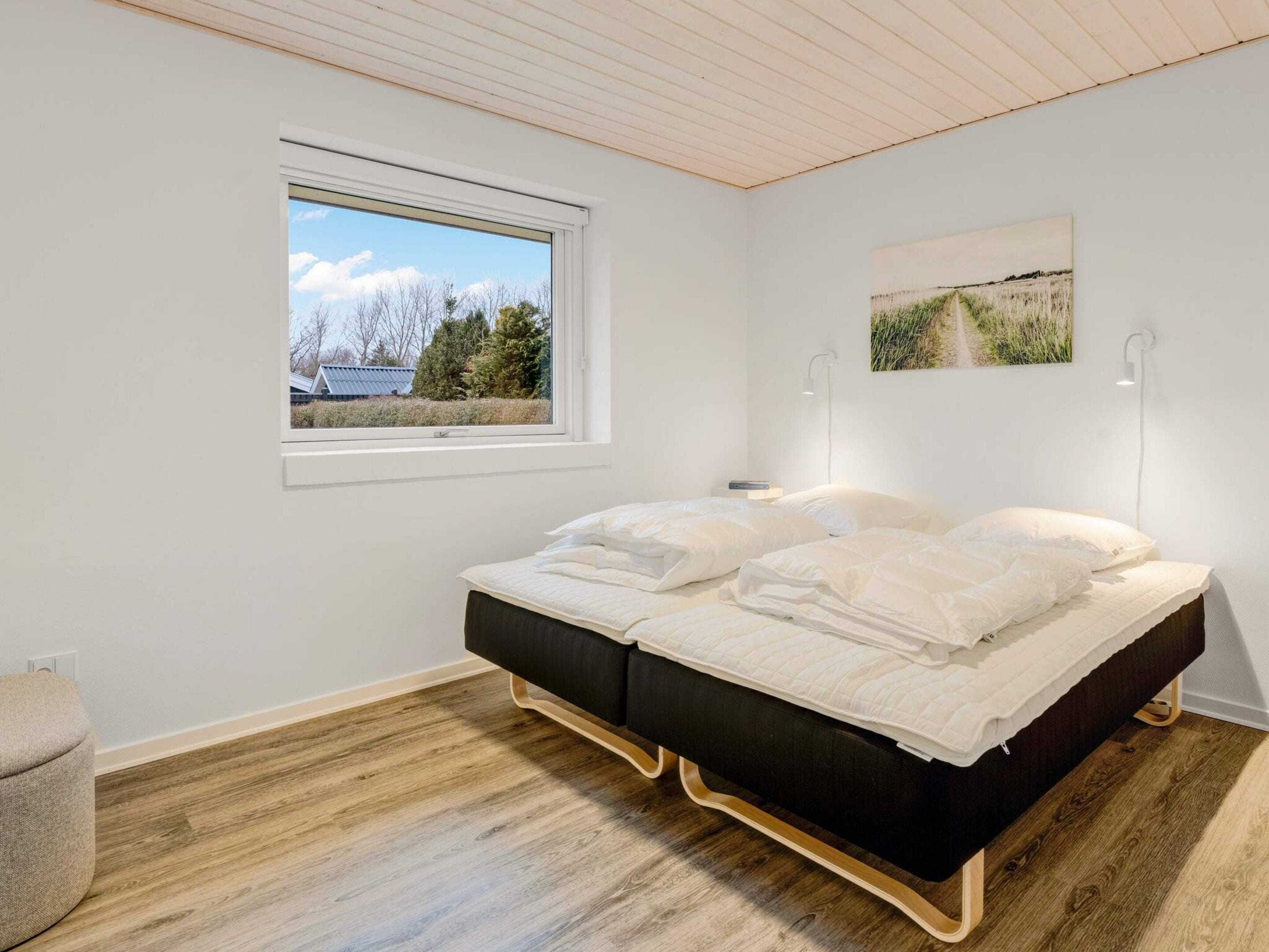 Un dormitorio con cama, ventana y lámpara fijada a la pared.