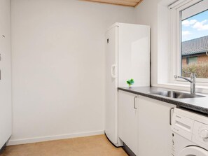 Une cuisine compacte dotée d’un lave-vaisselle encastré, d’une petite fenêtre et d’une plante en pot posée sur le plan de travail.