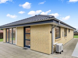 A single-story building with a tiled roof, a brick facade, and a large sliding glass door.