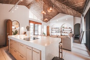 Eine moderne Küche mit einer großen Kochinsel, Holzschränken und einer rustikalen Decke.