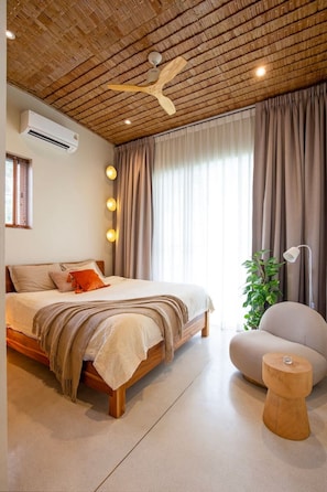 A modern bedroom with a wooden ceiling, a bed with beige bedding, a bedside lamp, and a potted plant. - Charming 2-BR Seaside Haven (Ko Pha-ngan)