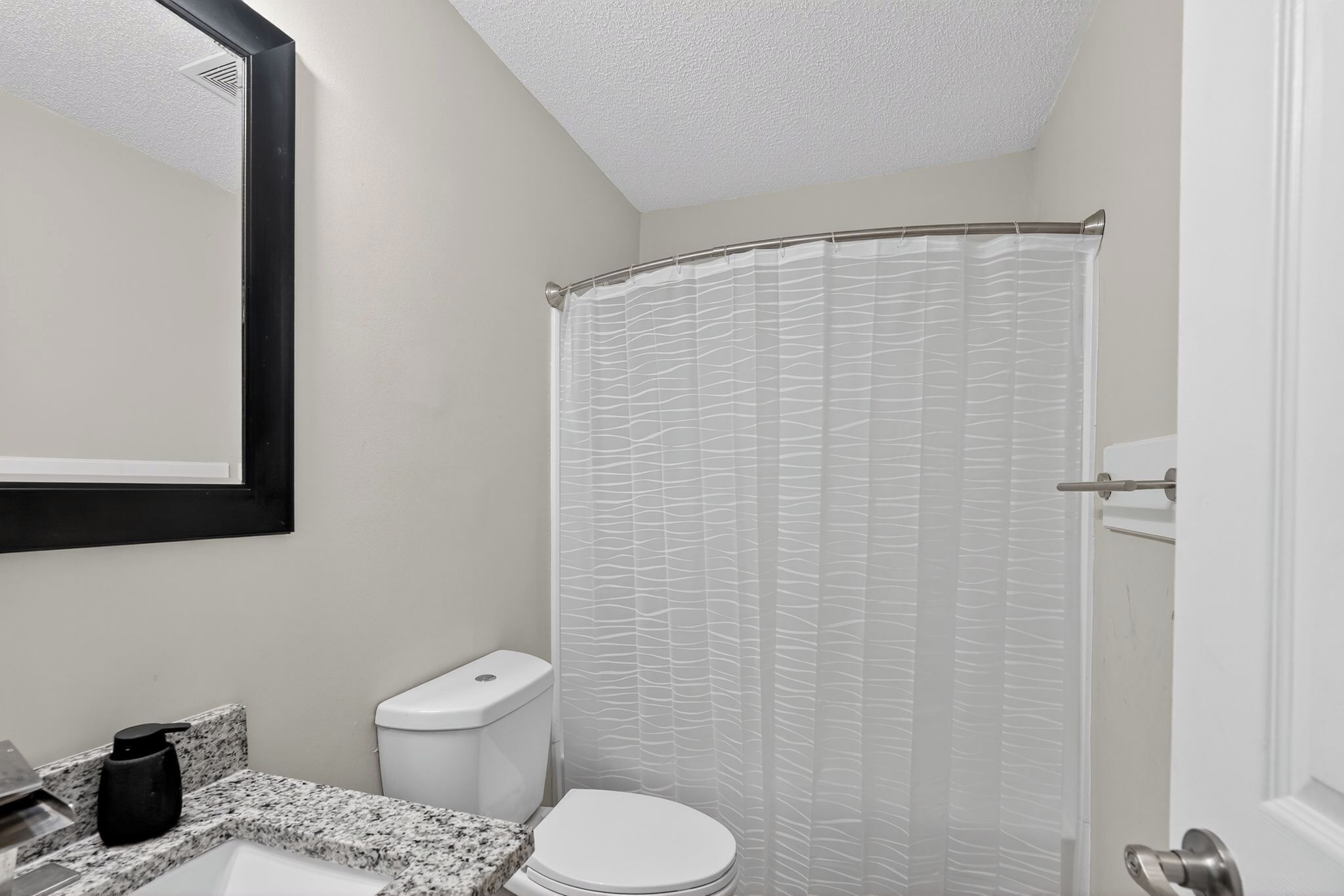 A bathroom with a toilet, sink, and shower curtain.
