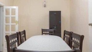 Une pièce avec un grand lit rectangulaire, une table de chevet en bois et une porte.