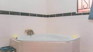 Une salle de bain avec une baignoire, une poubelle et un porte-serviettes.