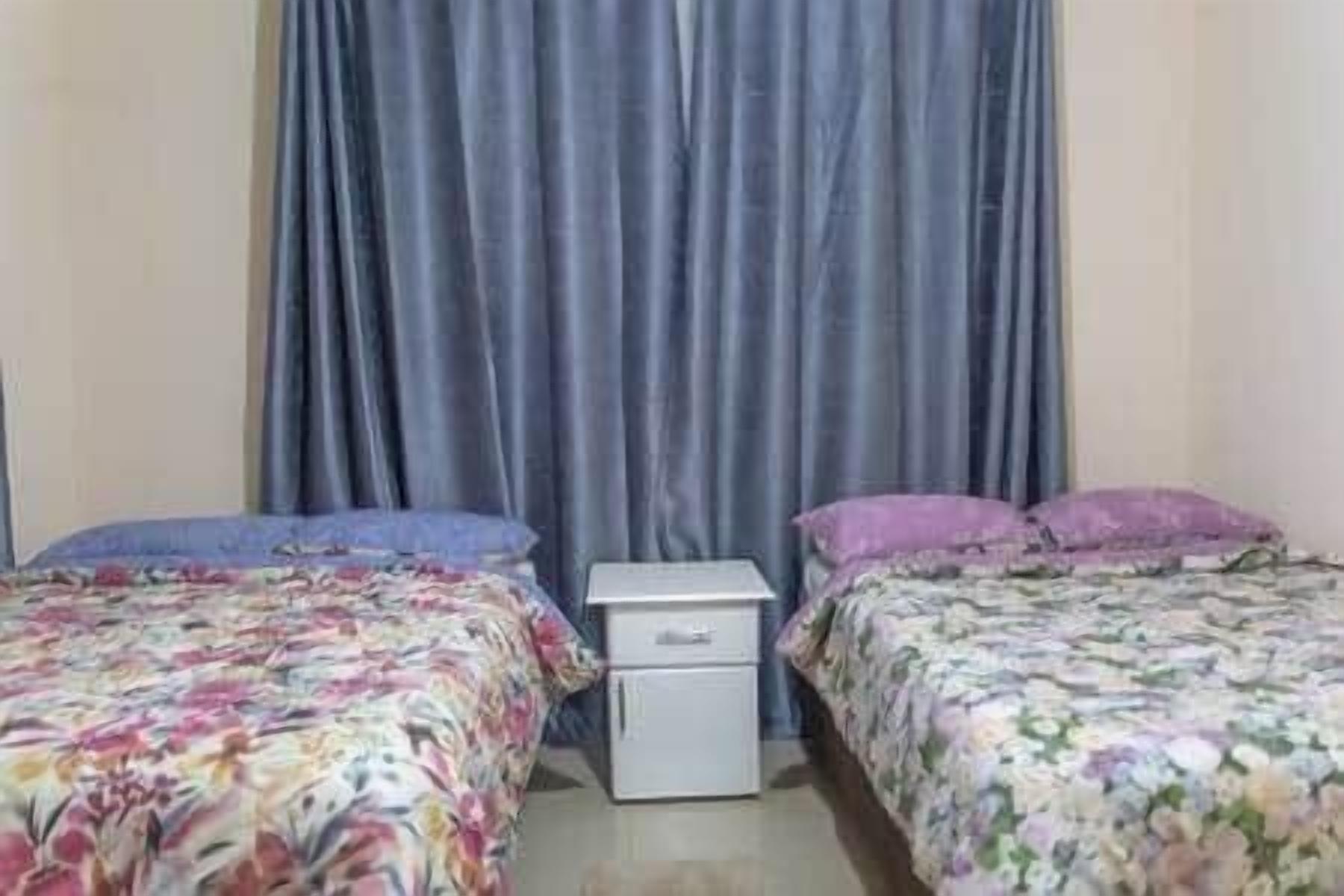 Een slaapkamer met twee bedden, een nachtkastje en een klein wit kastje.