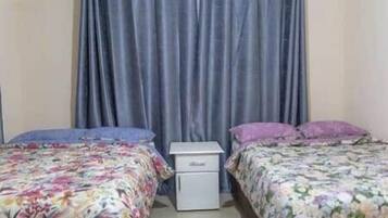 Een slaapkamer met twee bedden, een nachtkastje en een klein wit kastje.
