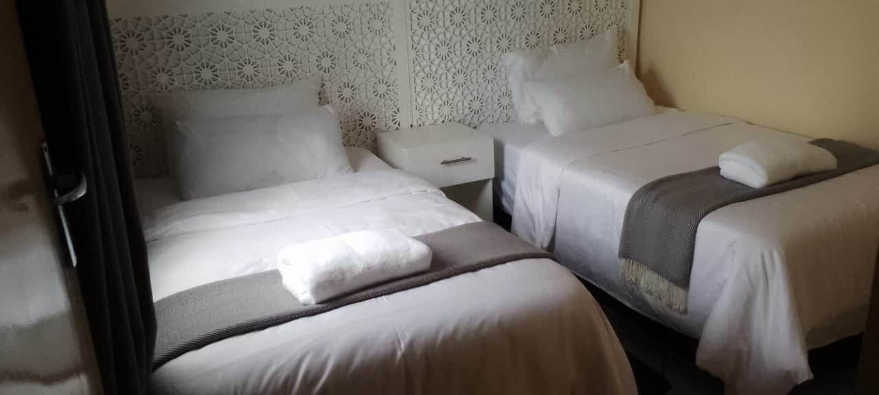 Una habitación de hotel con dos camas, una mesita de noche y un panel decorativo en la pared.