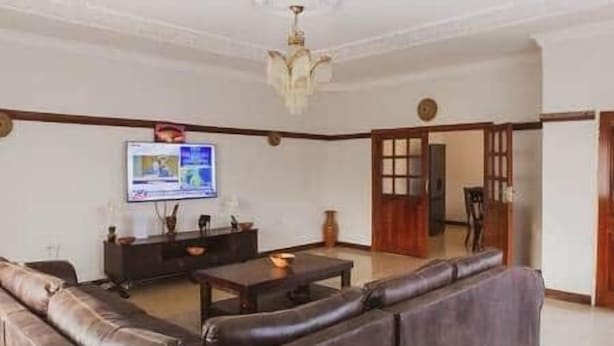 Ein Wohnzimmer mit einer Couch, einem Couchtisch und einem an der Wand befestigten Fernseher.